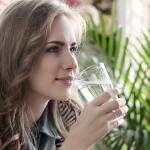 Una mujer disfruta de un vaso de agua pura y de calidad gracias a los sistemas de tratamiento del agua de AquaWorld Canarias