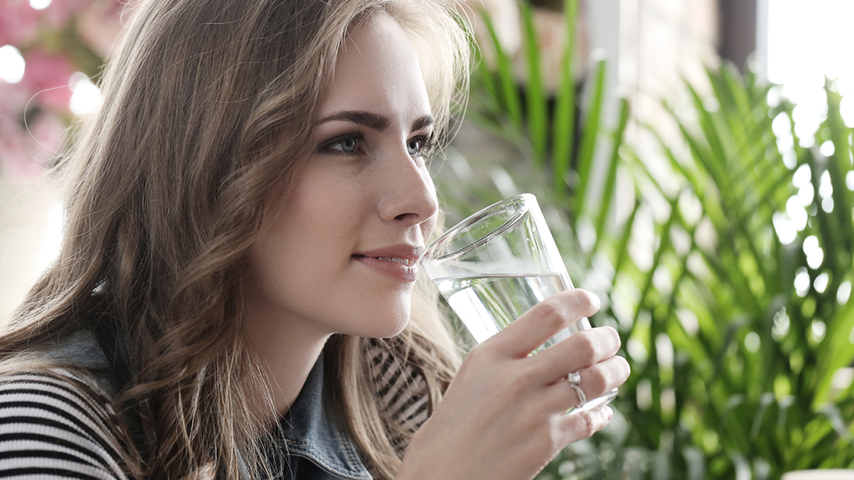 Una mujer disfruta de un vaso de agua pura y de calidad gracias a los sistemas de tratamiento del agua de AquaWorld Canarias